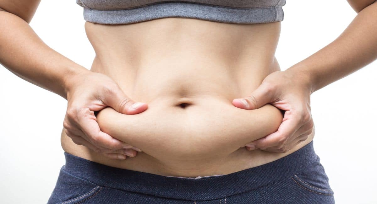 a woman squeezing her abdominal fat 